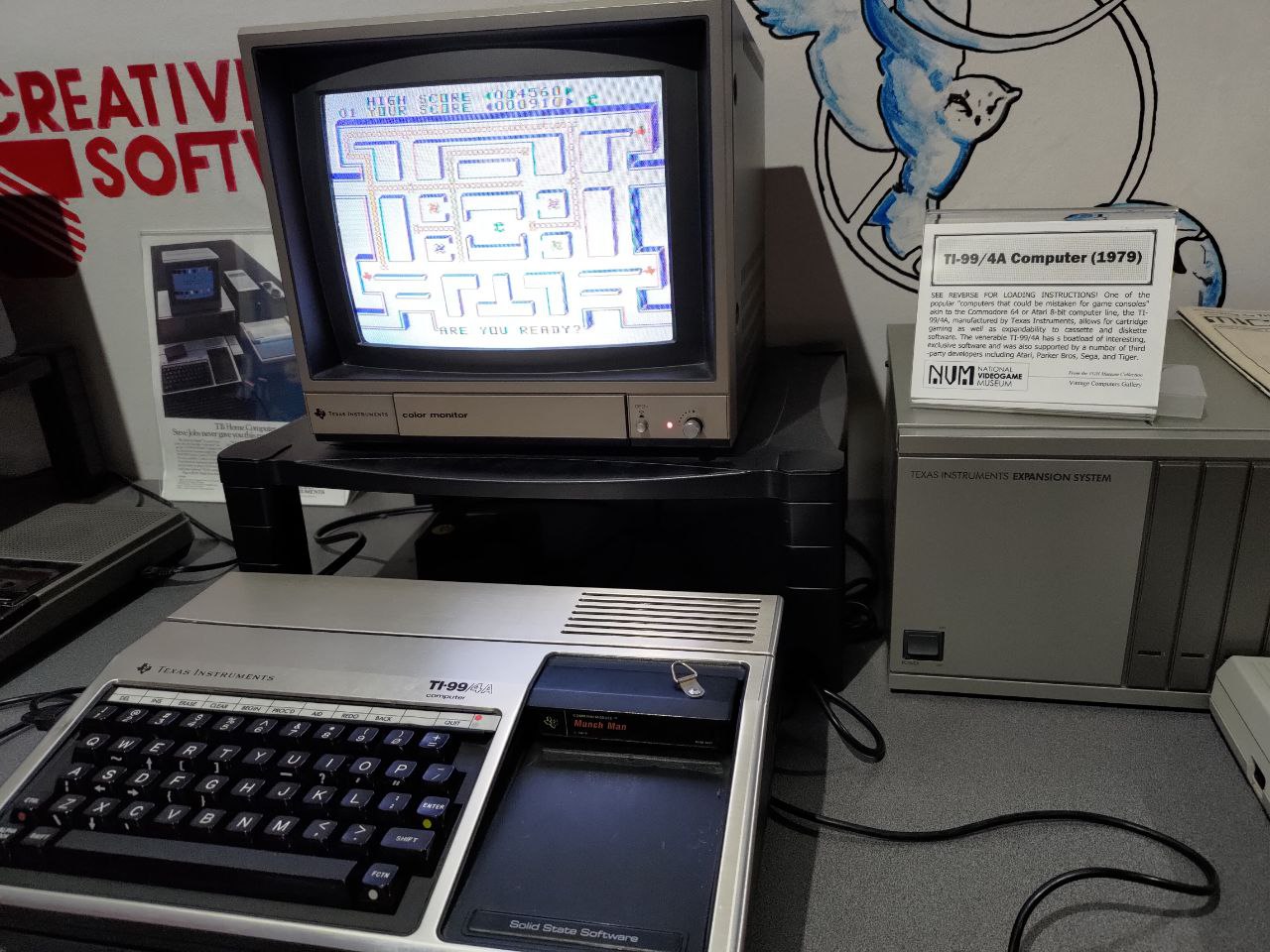 A TI-99/4A Computer on display in the National Videogame Museum. On the screen is a rudimentary maze game similar to Pac-Man
